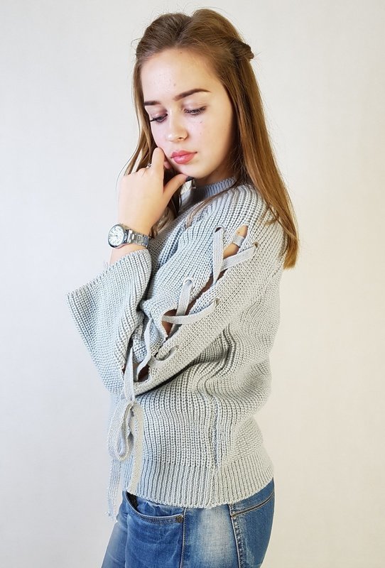 Девушка в свитере с завязками вдоль рукавов